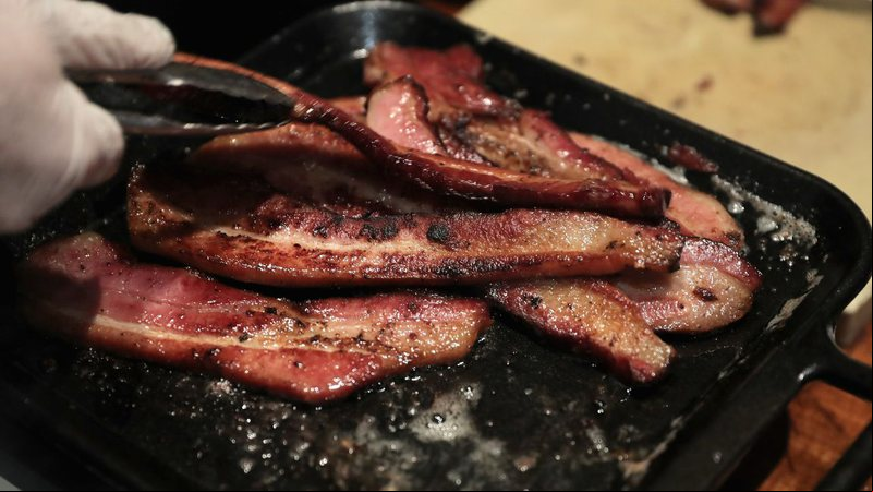 Imagem ilustrativa de pessoa cozinhando bacon - Getty Images